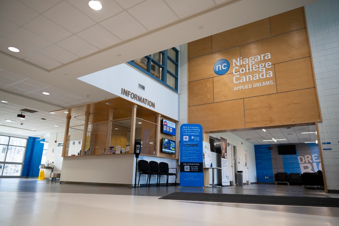 Niagara College Canada campus interior featuring an information desk, seating area, and inclusive wall signage.