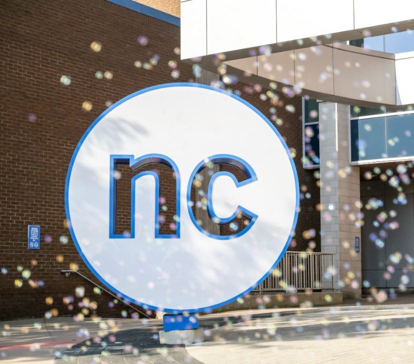 Large Niagara College "nc" sign outside a brick building with a "Welcome" banner and bubbles floating in the foreground.